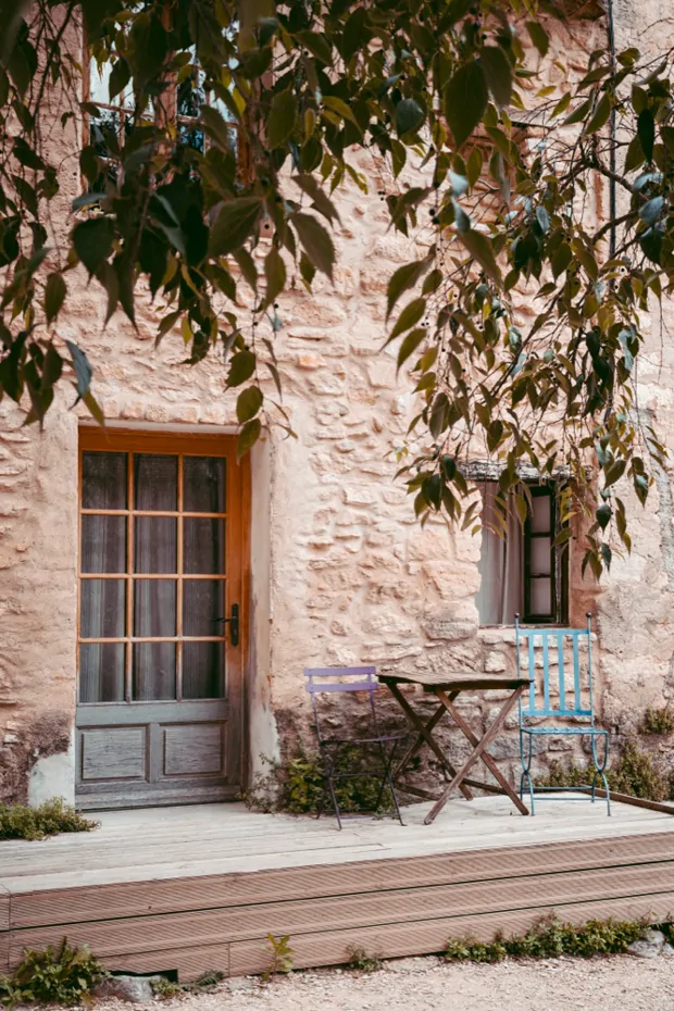 A table and chairs on a terrace beside a shuttered window