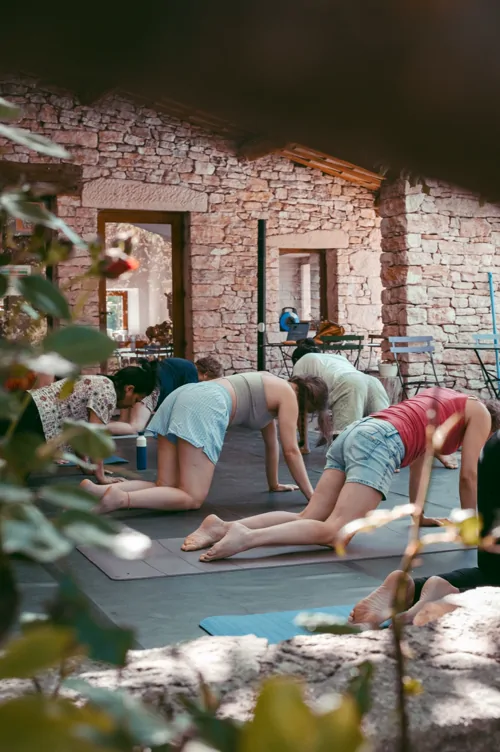 Dancers practising yoga on a shaded stone terrace